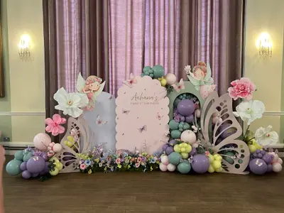 Event styling & planning in Leicester by Lulu Belle Events. Lilac/purple, sage green, pale pink, white, yellow-green, teal. Organic clustered garland at ground level with balloons of mixed sizes. Event theme Fairy. Soft pink, lilac/purple, sage green, pale blue, yellow-green, white, with pink floral accents.