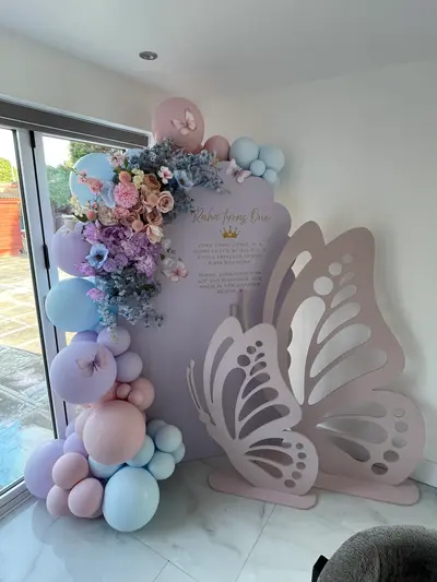 Event styling & planning by Lulu Belle Events. Domestic interior room with marble-effect tiled floor, white walls, and sliding glass patio doors. Pastel pink, baby blue, lilac, dusky mauve with gold accent.