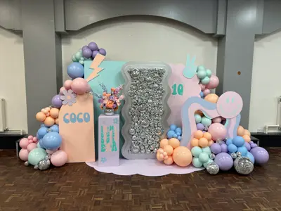 Birthday decor in Cosby by Lulu Belle Events. Large organic balloon garland wrapping around the left side and top of the backdrop. Pink, peach, lilac, purple, mint, baby blue with silver disco ball ornaments interspersed. Organic garland with varied balloon sizes including large statement balloons and small fill balloons.