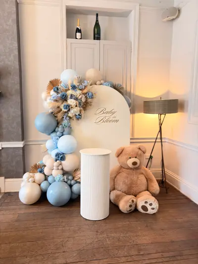 Event styling & planning in Leicester by Lulu Belle Events. Boho baby shower with dried botanicals and soft blue palette. Arch / rounded-top panel. Organic balloon garland running from ground up the left side and across the top of the arch. Baby blue, dusty blue, cream, sand/nude, white.