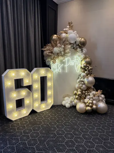 Event styling & planning in Leicester by Lulu Belle Events. Indoor function room or hotel ballroom with dark grey patterned carpet and dark grey floor-length curtain drapery on the wall. White, chrome gold, champagne/nude, and bronze/brown tones.