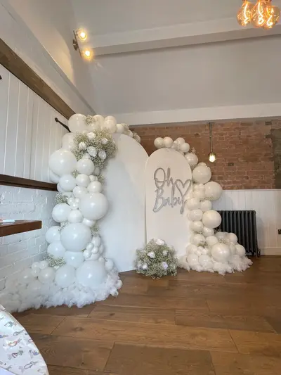 Baby shower decor in Gilmorton by Lulu Belle Events. Soft cloud / neutral baby shower. All white with soft grey/silver signage accents. Full organic balloon garland wrapping around both sides and across the top of the arch backdrop. All white, mixed sizes from small to oversized.